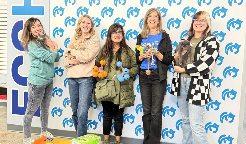 Group with Cats and Pet Supplies in Front of Branded Wall